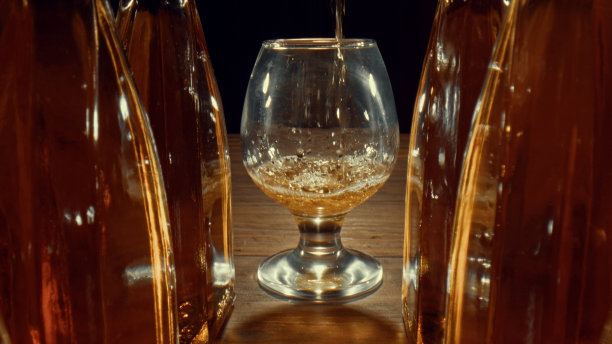 饮料正倒在干邑和威士忌旁边的玻璃杯里图片下载