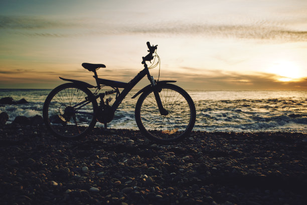傍晚，一辆山地车停在卵石海滩上图片下载