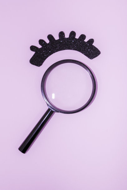 睫毛扩展。闪亮的黑色纸睫毛，粉色背景上的放大镜。图片下载