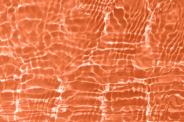 离焦模糊透明橙色透明平静的水面纹理与飞溅和气泡。潮流抽象的自然背景。水波在阳光下带有焦散。橘色水光图片下载