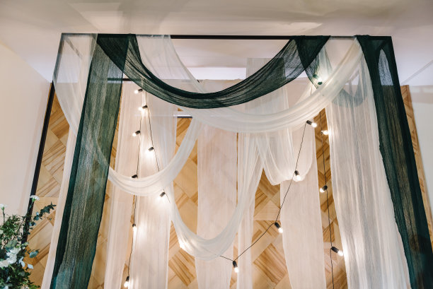 婚礼金属拱门用白色和绿色的纺织织物和灯泡的花环装饰。饭店婚礼用的鲜花和绿色植物装饰图片下载