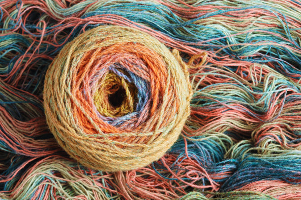 由纯有机羊毛制成的纱线球，绕在一束羊毛线上。彩虹的颜色。图片下载