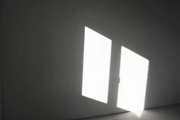灰色墙壁上窗户的影子。抽象的背景与阳光反射在垂直表面在黑暗中。图片下载