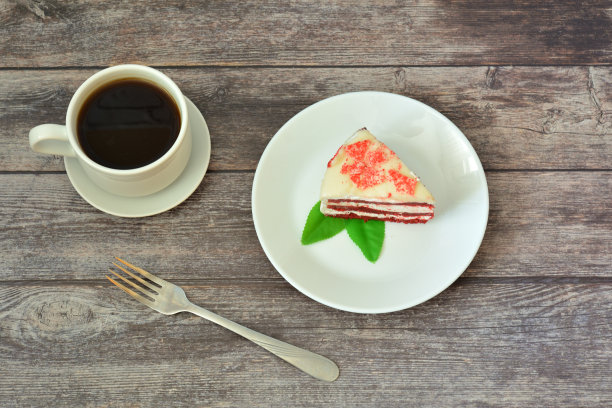 木桌上放着一块红丝绒蛋糕、热咖啡和一把叉子。图片下载