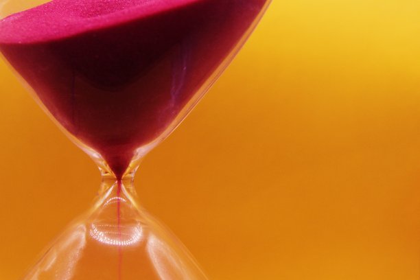 微距照片，玻璃沙漏细节在明亮的黄色背景。图片下载