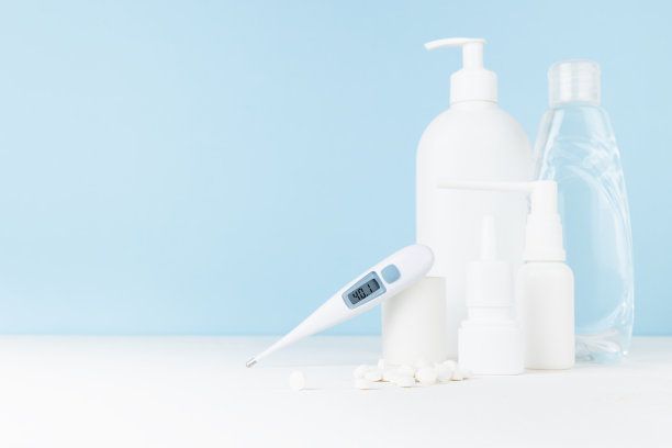 医疗和治疗药物-用于预防、治疗疾病、流感、普通感冒、病毒的白色瓶子- 40,1发热温度计，喷雾剂，药片，白色桌子上的消毒剂，蓝色墙壁，复制空间。图片下载