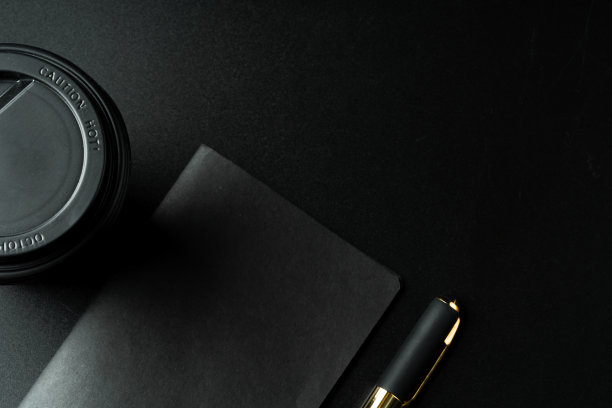 黑色的记事本和钢笔放在黑色的桌子上图片下载