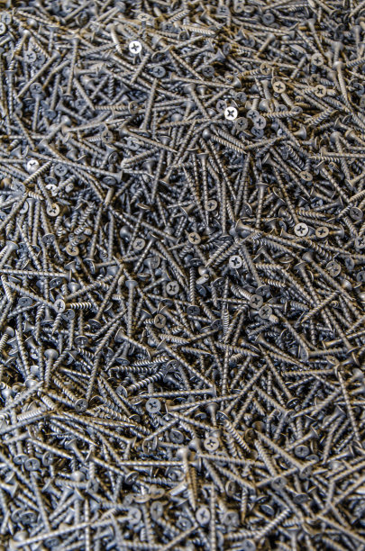 很多黑色的小螺丝。纹理，一堆螺丝散落在周围。螺丝纹理背景图片下载
