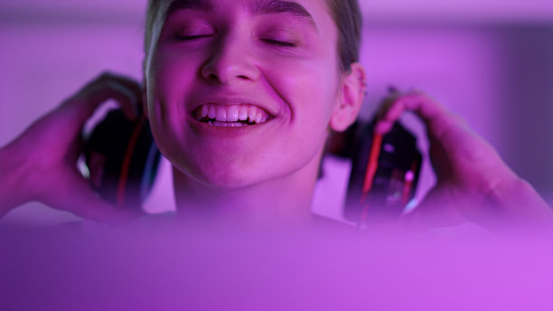 电子竞技女孩看电脑屏幕特写。快乐赢家摘下耳机。图片下载