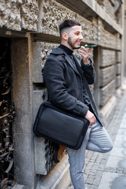 一个男人一边走在城市的街道上一边用手机。图片下载