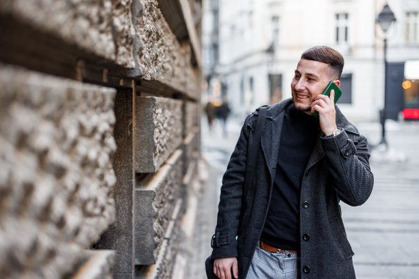 一个男人一边走在城市的街道上一边用手机。图片下载