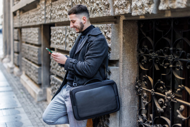 一个男人站在城市的街道上用手机。图片下载