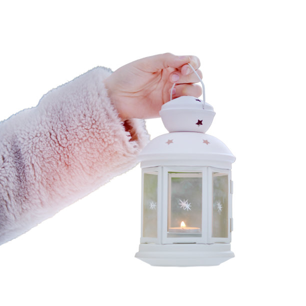 一个女人手里拿着一盏灯，里面有一根蜡烛，一个冬天的森林，雪中有树木，孤立在白色的背景上图片下载