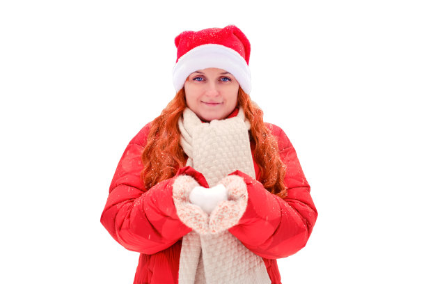 一名女子手持心形的雪，戴着针织手套，孤立在白色背景上。红头发的女人在圣诞节和新年前夜穿着红色的衣服走在冬天图片下载