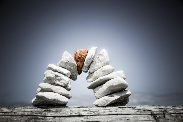 蓝色的天空下，鹅卵石砌成红色拱心石的石桥图片下载