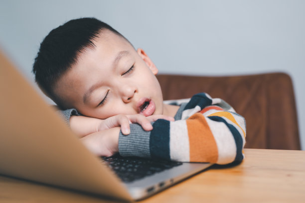 亚洲男孩在笔记本电脑上上网学习时睡觉。图片下载
