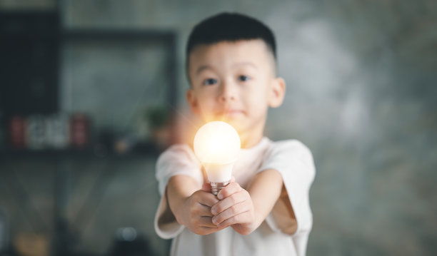 一个男孩，一个拥有明亮灯泡的孩子。概念的想法，提出新的想法伟大的灵感和创新新的开始。图片下载