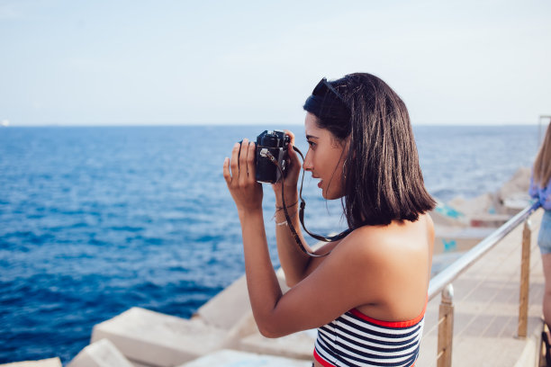 专注的女人在相机上拍摄海景照片图片下载