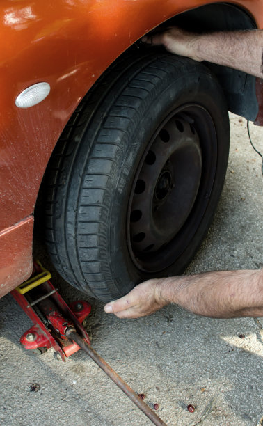 汽车修理工在街上拿起千斤顶换轮胎图片下载
