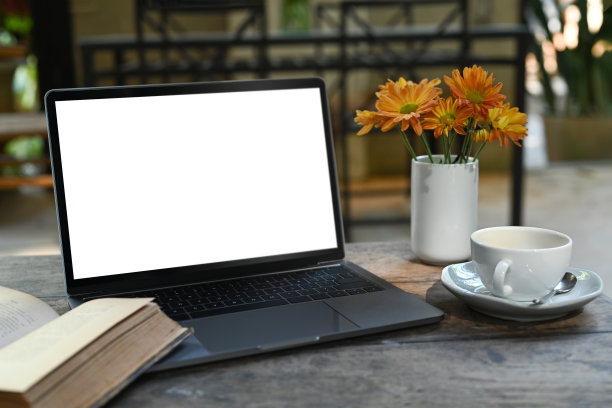 舒适的工作场所，笔记本电脑，书，咖啡，书和花瓶黄花在质朴的木桌上。图片下载