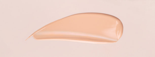 米色背景上的化妆品涂抹粉底霜图片下载