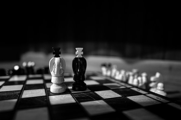 模糊的黑白背景与低深度的焦点。一套木制棋子元素站在棋盘上的黑暗背景。领导力，团队合作，伙伴关系，商业战略理念。图片下载