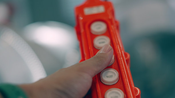 工人手握起重机控制按钮。上下液压控制开关。电动遥控按钮开关，用于提升机或起重机的控制方向。工业，工厂，制造业。图片下载