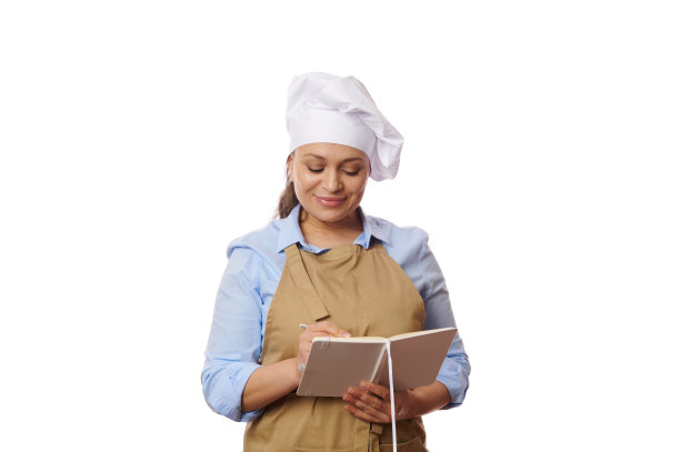 美丽的多民族女性，米色围裙的厨师或面包师，在白色背景的记事本上写字图片下载