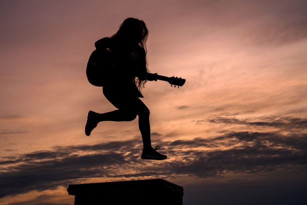 剪影女子在日落弹吉他图片下载