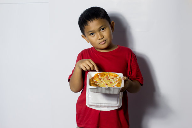 亚洲男孩吃白色背景的披萨图片下载