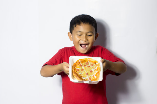 亚洲男孩吃白色背景的披萨图片下载