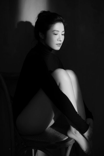 一个东亚女人坐在木椅上的垂直镜头图片下载