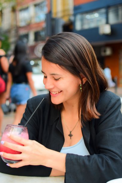一名女性在街头咖啡馆笑着喝着一杯奶昔的垂直镜头图片下载