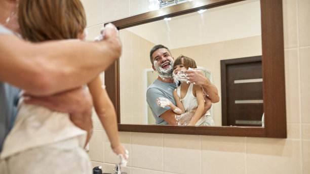 镜子里父亲在男孩脸上涂抹剃须泡沫图片下载