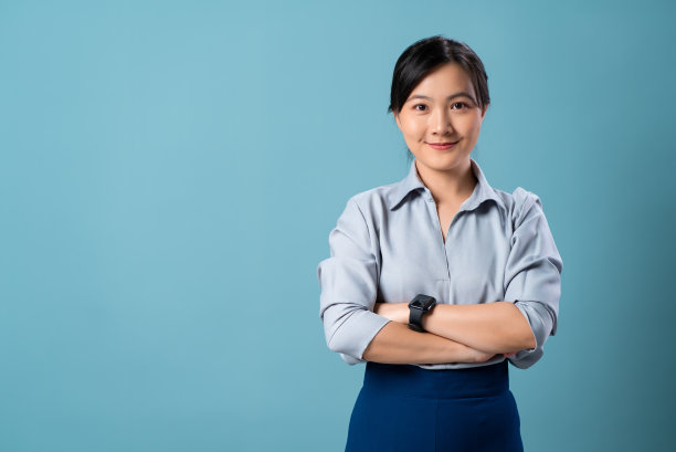 亚洲妇女高兴地微笑着，看着相机孤立在蓝色的背景。图片下载