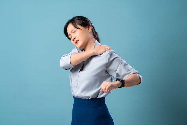 一名肩膀疼痛的亚洲妇女孤立地站在蓝色背景上。图片下载