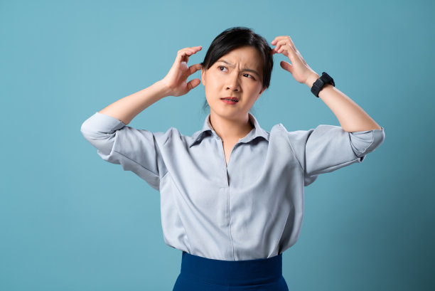 亚洲妇女头皮发痒，抓耳挠腮，孤立地站在蓝色背景上。图片下载