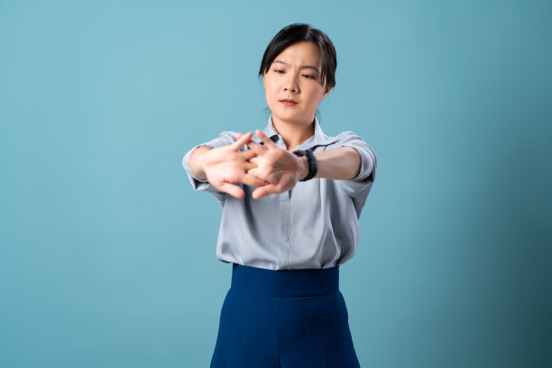 亚洲妇女孤立地站在蓝色背景上，手受伤，感到疼痛。图片下载