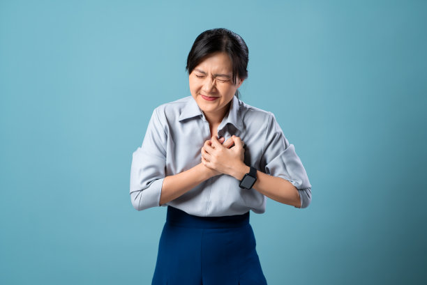 亚洲女性胸痛严重，孤立地站在蓝色背景上。图片下载