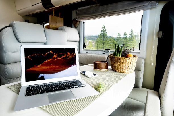 自由智能工作或数字游牧生活方式的替代办公室和工作站概念。笔记本电脑放在汽车之家的桌子上，窗外是自然和自由的风景。工作活动图片下载
