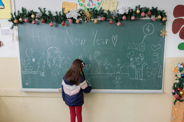 小学女生在黑板上画画，装饰教室迎接新年图片下载