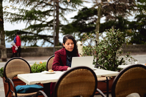 自由职业者旅行者使用笔记本电脑在线工作，享受早餐。图片下载