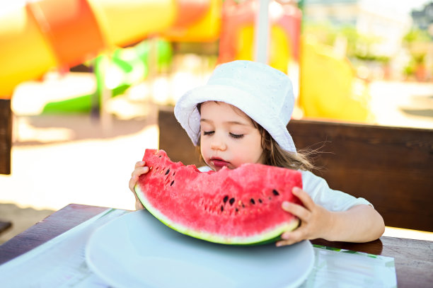 夏天的心情。孩子的发展。意大利的一个儿童游乐场里，蹒跚学步的孩子正在吃东西。图片下载