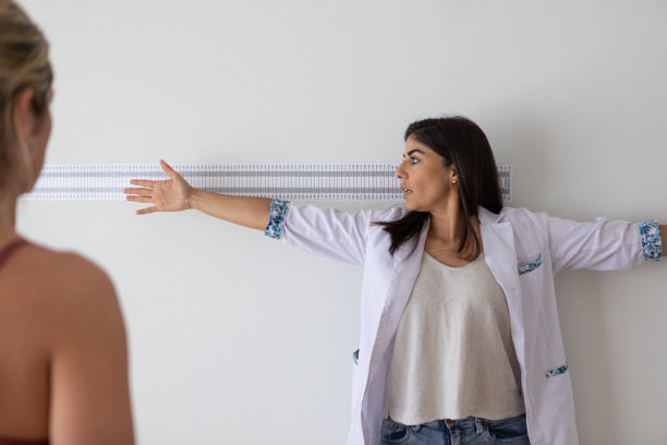 女性营养学家和出境学家在医疗咨询期间向女性病人展示如何站起来测量四肢图片下载