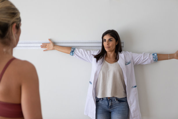 女性营养学家和出境学家在医疗咨询期间向女性病人展示如何站起来测量四肢图片下载