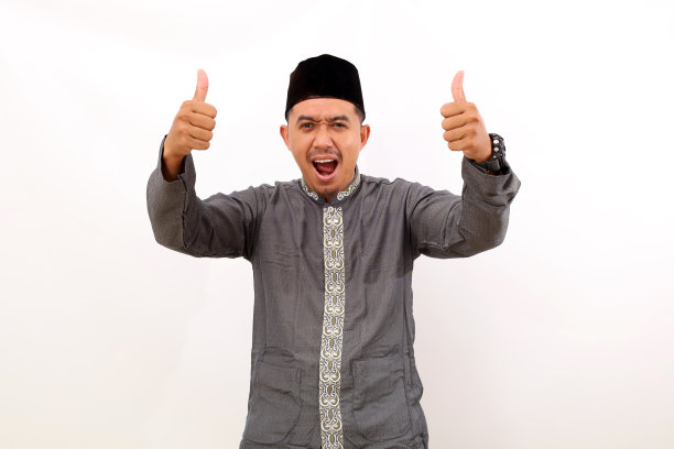 兴奋的亚洲穆斯林男子站着，竖起大拇指。白色背景隔离图片下载