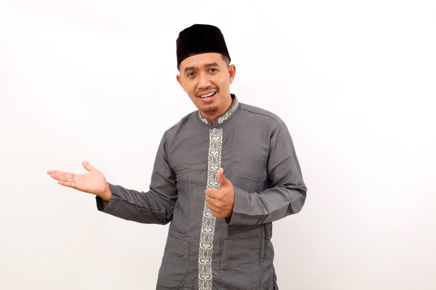 快乐的亚洲穆斯林男子站着，展示一些东西，竖起大拇指。白色背景隔离图片下载