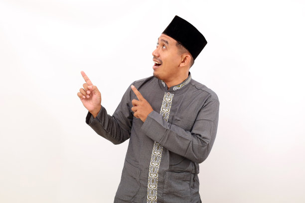 快乐的亚洲穆斯林男子站着，指着他上面的东西。白色背景隔离图片下载