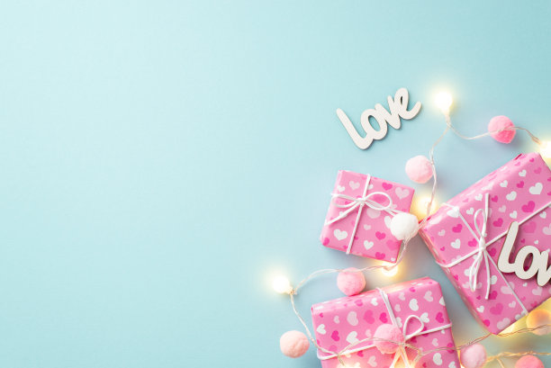 情人节的概念。顶部视图照片的礼物盒包装爱心图案灯泡花环铭文爱和软绒球在孤立的粉彩蓝色背景与复制空间图片下载