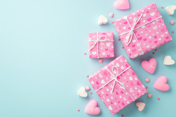 情人节的概念。顶部视图照片粉红色的礼物盒心形棉花糖蜡烛和洒在孤立的浅蓝色背景与复制空间图片下载